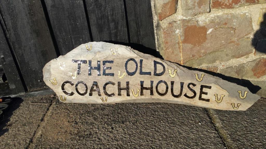 a sign that says the old coach house on the side of a building at The Old Coach House in Iddesleigh