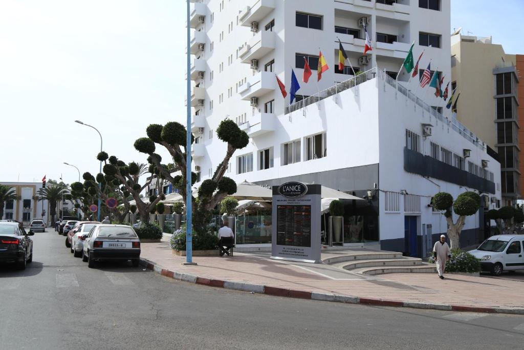 a large white building with cars parked on a street at Studiotel Afoud in Agadir
