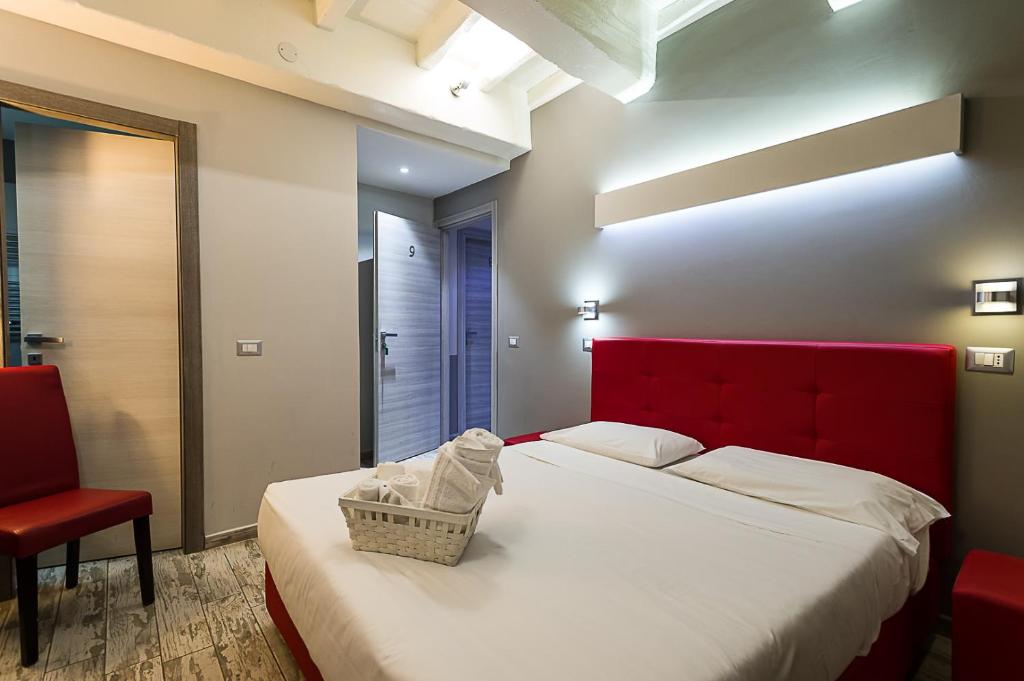 a bedroom with two beds with a red headboard and a chair at NL Trastevere in Rome