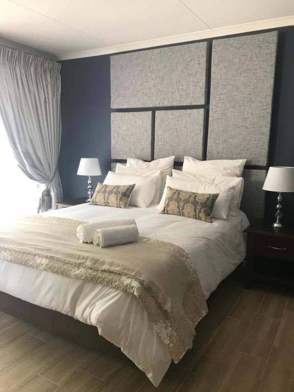 ein Schlafzimmer mit einem großen Bett mit weißer Bettwäsche und Kissen in der Unterkunft La Benroy in Klerksdorp