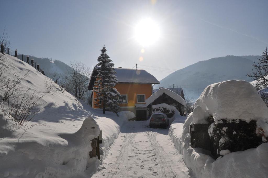 pokryta śniegiem ulica z domem i samochodem w obiekcie Privatzimmer Bendl w mieście Steinhaus am Semmering