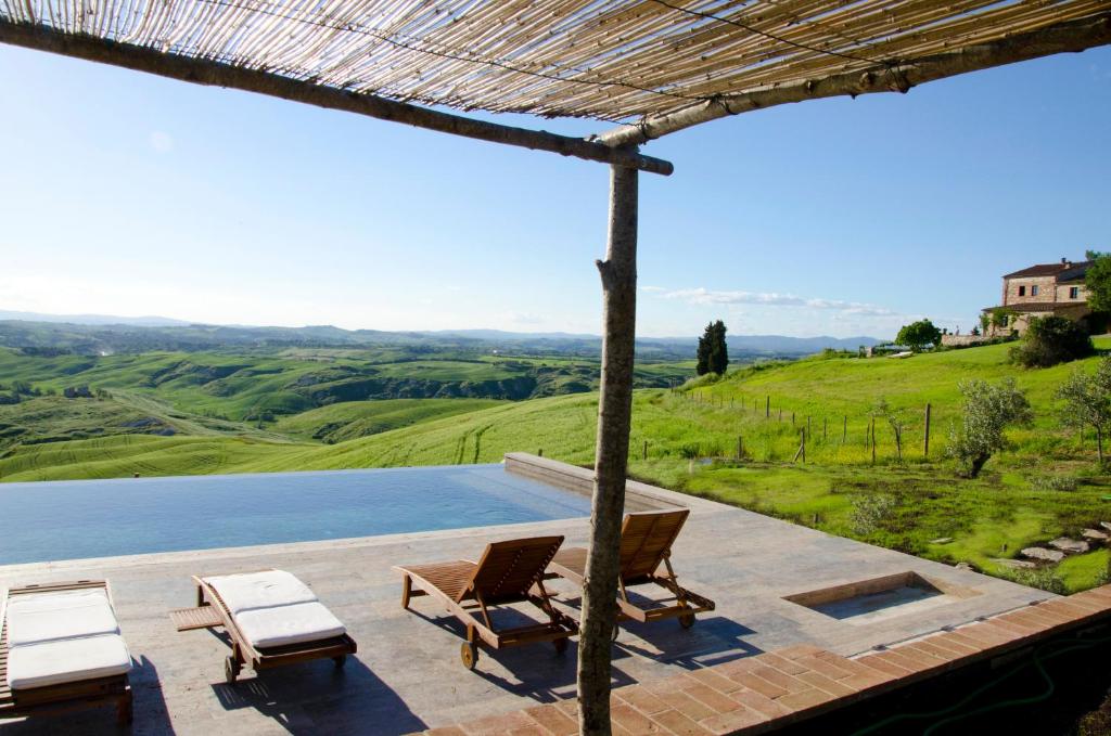 a patio with chairs and a view of a lake at The Lazy Olive Villa - Podere Finerri in Asciano