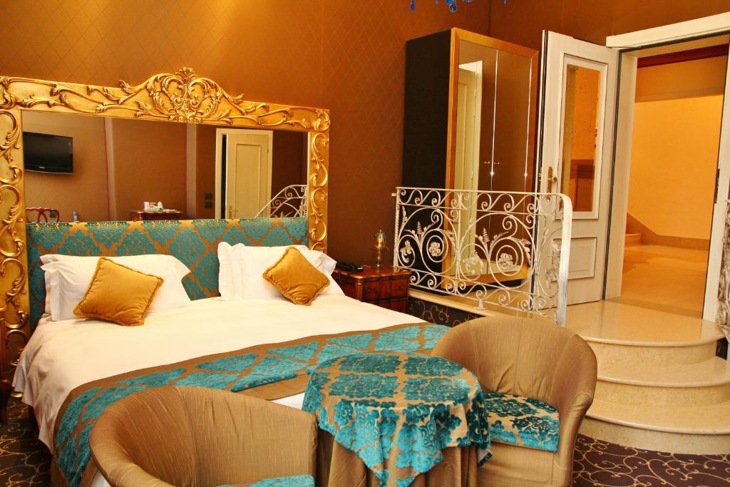 a bedroom with a bed and a mirror and chairs at Pesaro Palace in Venice
