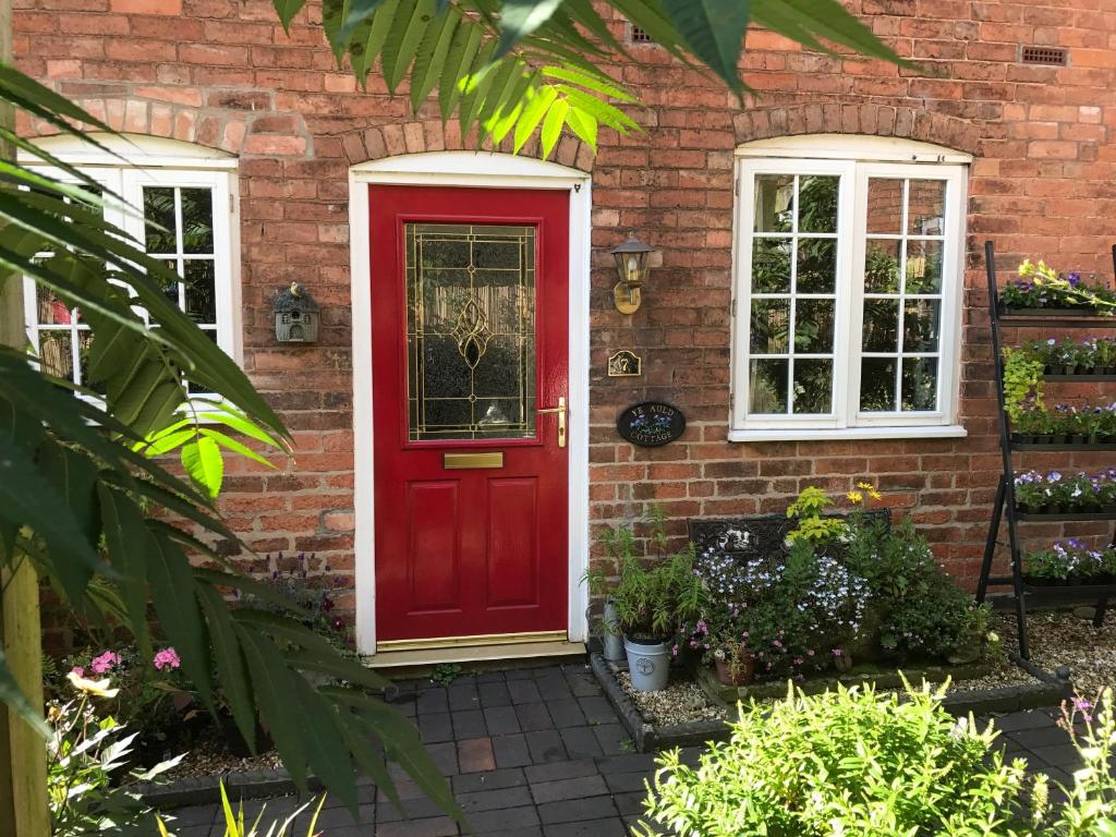 a red door on a brick house with two windows at Southwell in Southwell