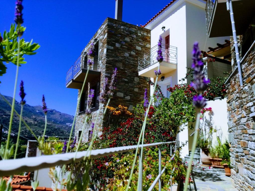 Una casa con flores al costado. en Rastoni Apartments, en Ándros