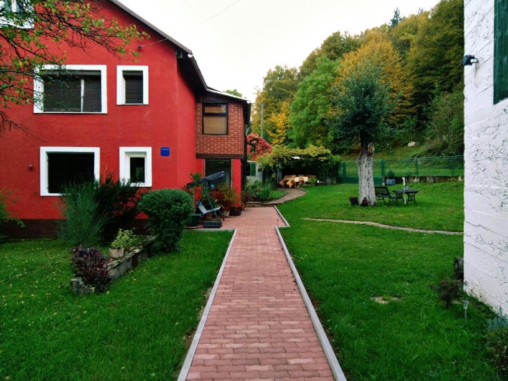 a red house with a brick walkway next to a yard at Holiday Home Modric in Otočac