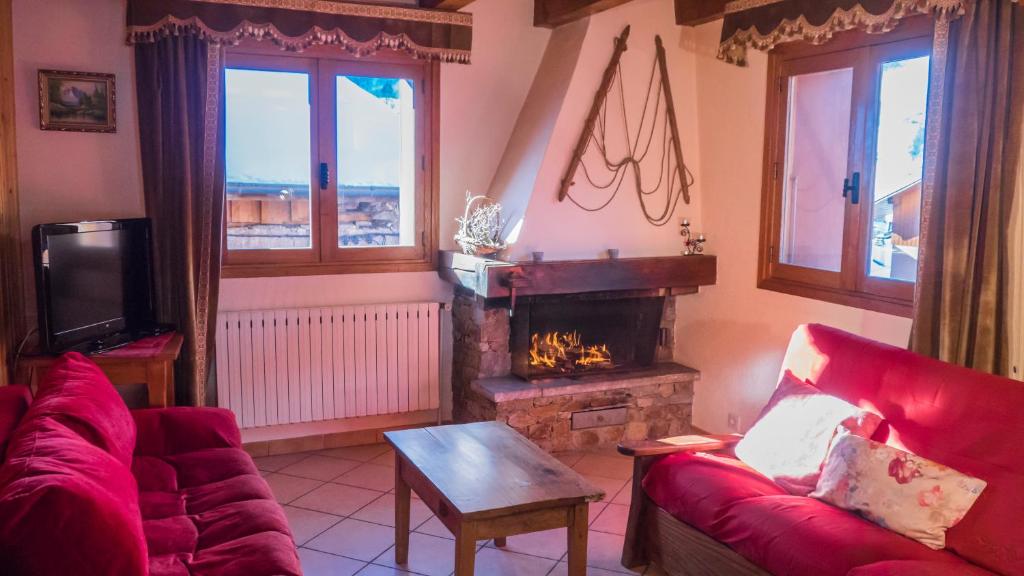 a living room with a fireplace and a red couch at Adret in Saint-Martin-de-Belleville