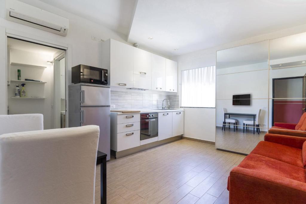 - une cuisine avec des placards blancs et un canapé rouge dans la chambre dans l'établissement PrimoPiano - Melzo A, à Milan