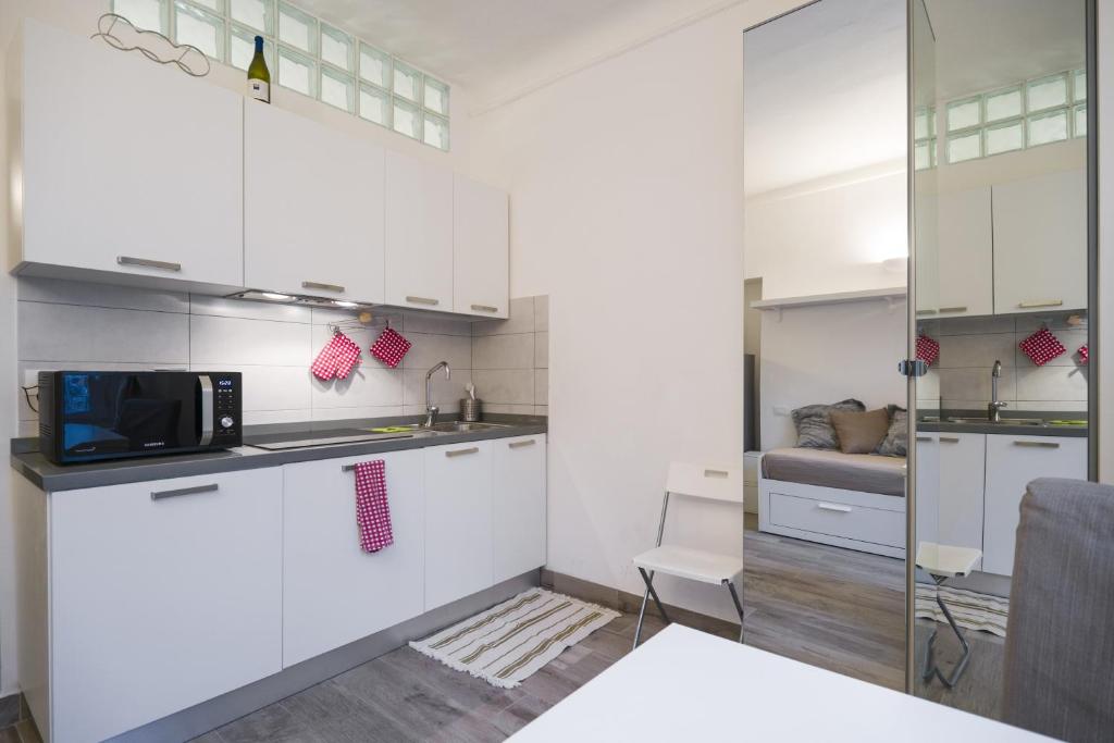 eine Küche mit weißen Schränken und einer Mikrowelle in der Unterkunft PrimoPiano - RG26 in Mailand