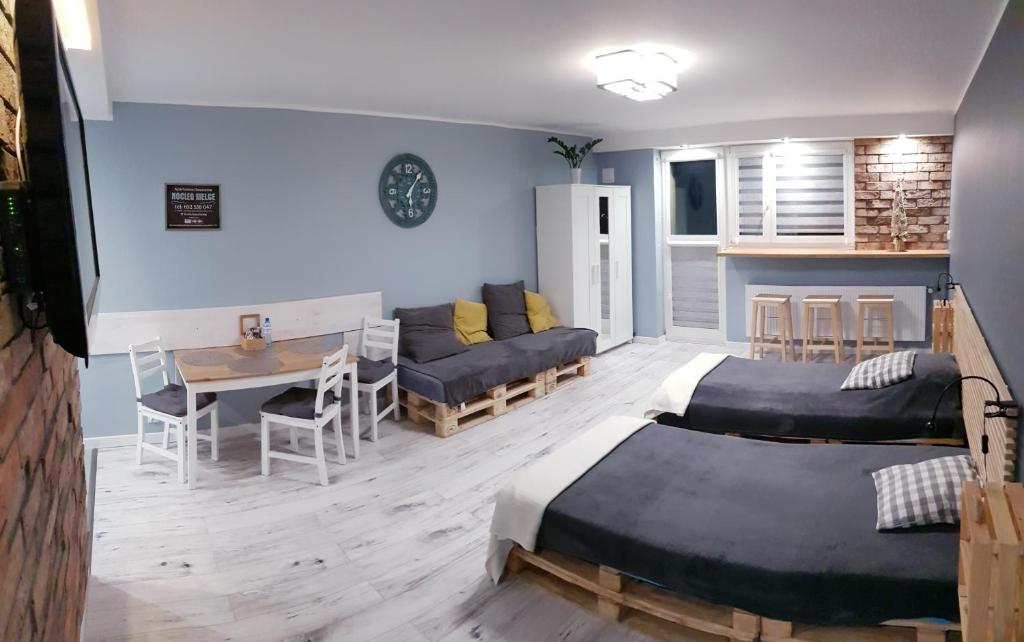 キェルツェにあるApartament Panoramaのベッド2台、テーブル、ソファが備わる客室です。