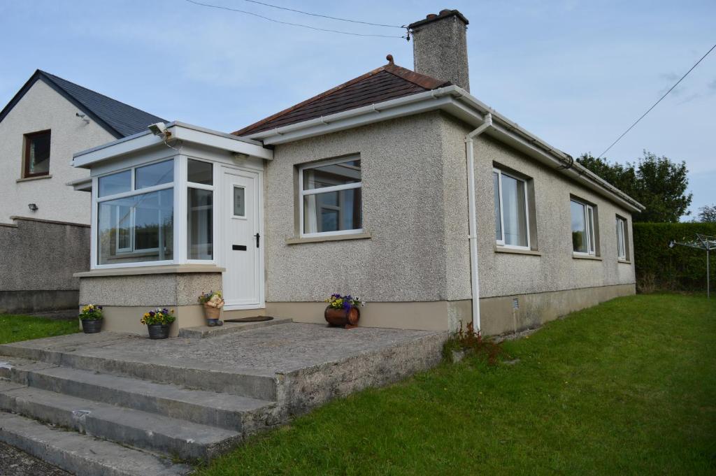 a small house with stairs in front of it at Drumahaman Cottage in Ballycastle