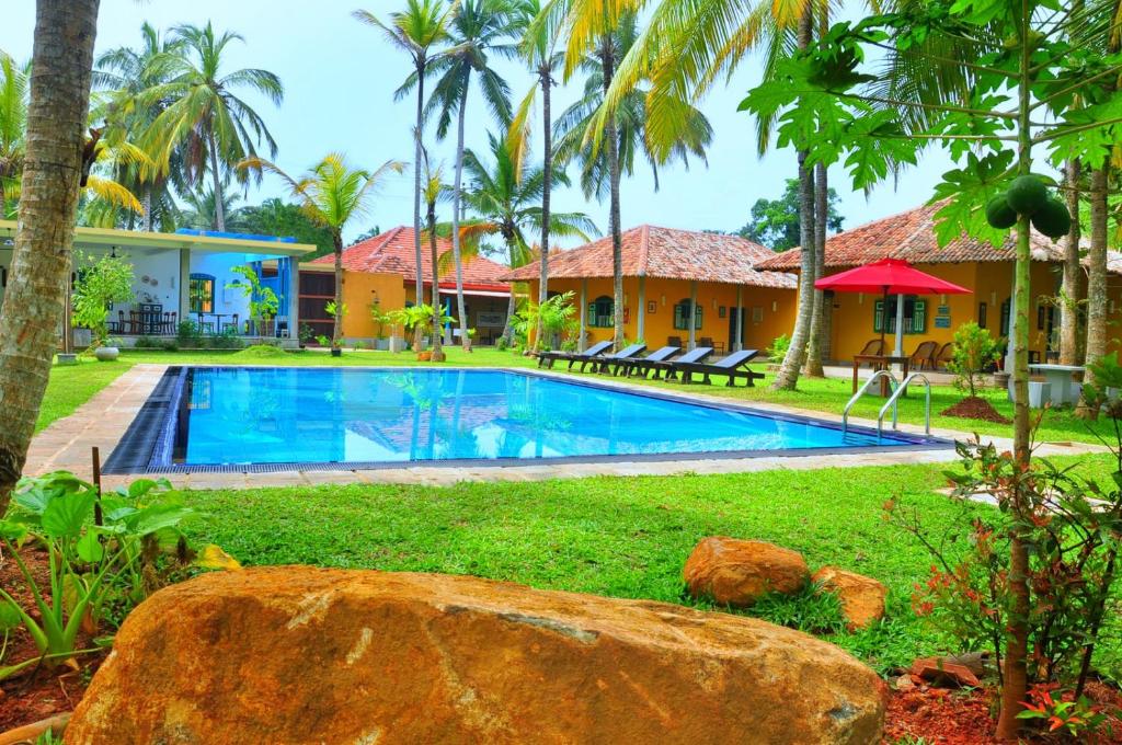 a swimming pool in front of a house with palm trees at Kurumba Villas in Bentota