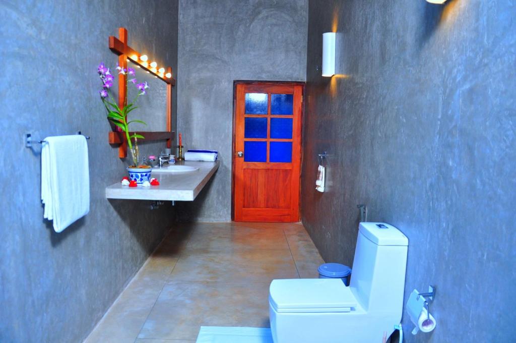 a bathroom with a toilet and a red door at Kurumba Villas in Bentota