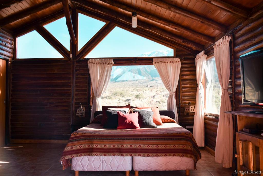 a bedroom with a bed with a large window at Cabañas Aventurados in Potrerillos