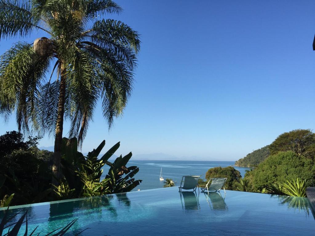 a swimming pool with two chairs and a view of the ocean at Casa Mar Paraty in Paraty