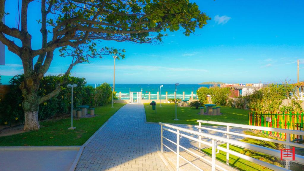 uma passagem que leva a um parque com uma árvore e o oceano em Ingleses Park Hotel em Florianópolis