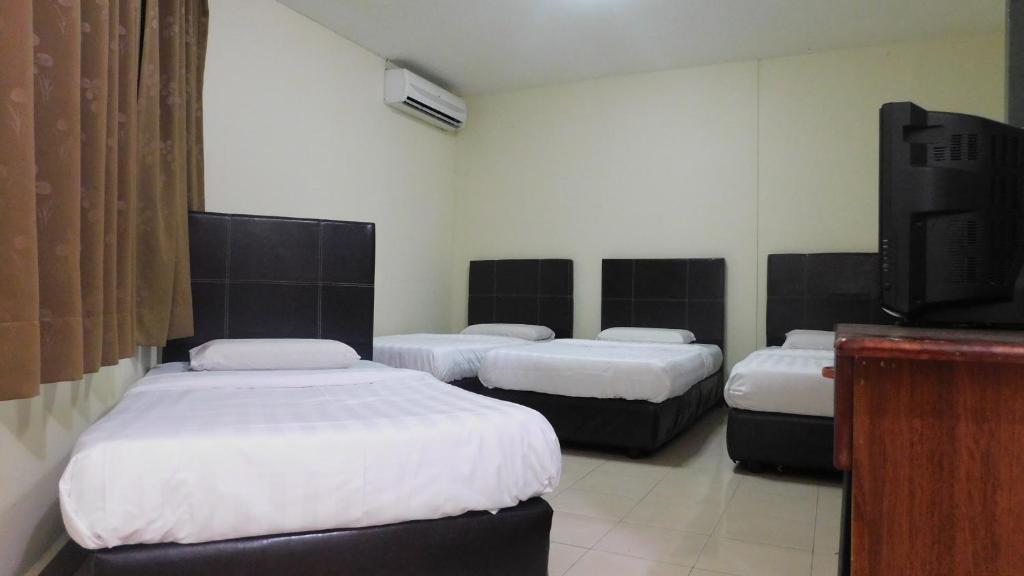 a room with three beds and a flat screen tv at Hotel Ocean in Lahad Datu