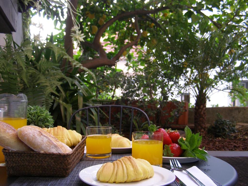 stół z dwoma talerzami chleba i sokiem pomarańczowym w obiekcie Encantadora Casa do Limoeiro w Lizbonie