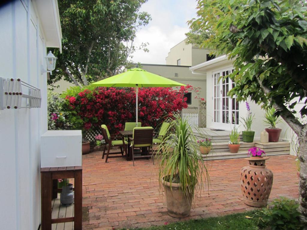 a patio with a green umbrella and some plants at Welbourn Accommodation in New Plymouth