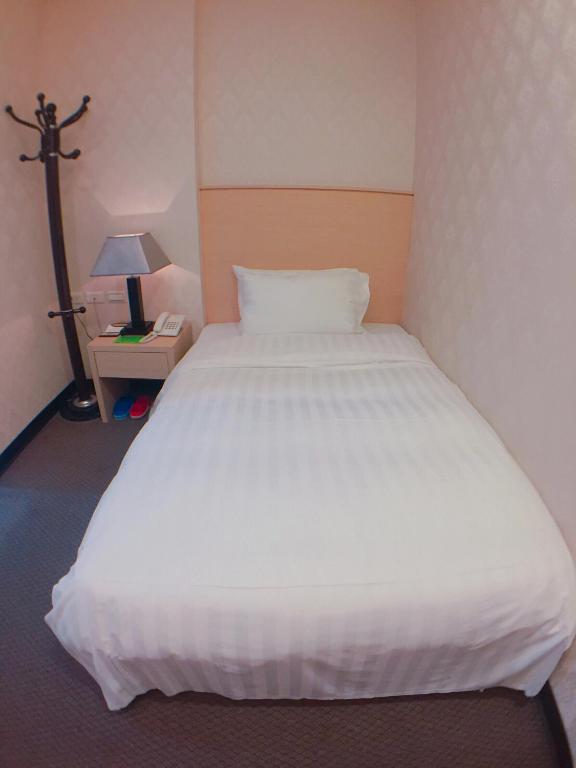 a large white bed in a room with a lamp at Royal Hotel in Taipei