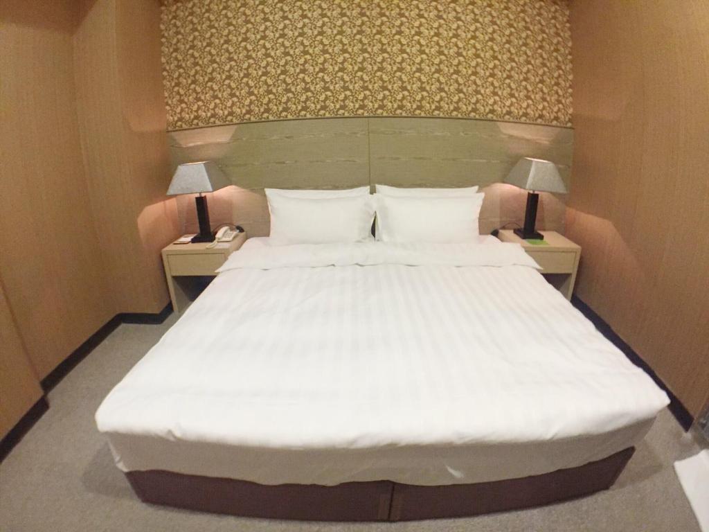 a bedroom with a large white bed with two lamps at Royal Hotel in Taipei