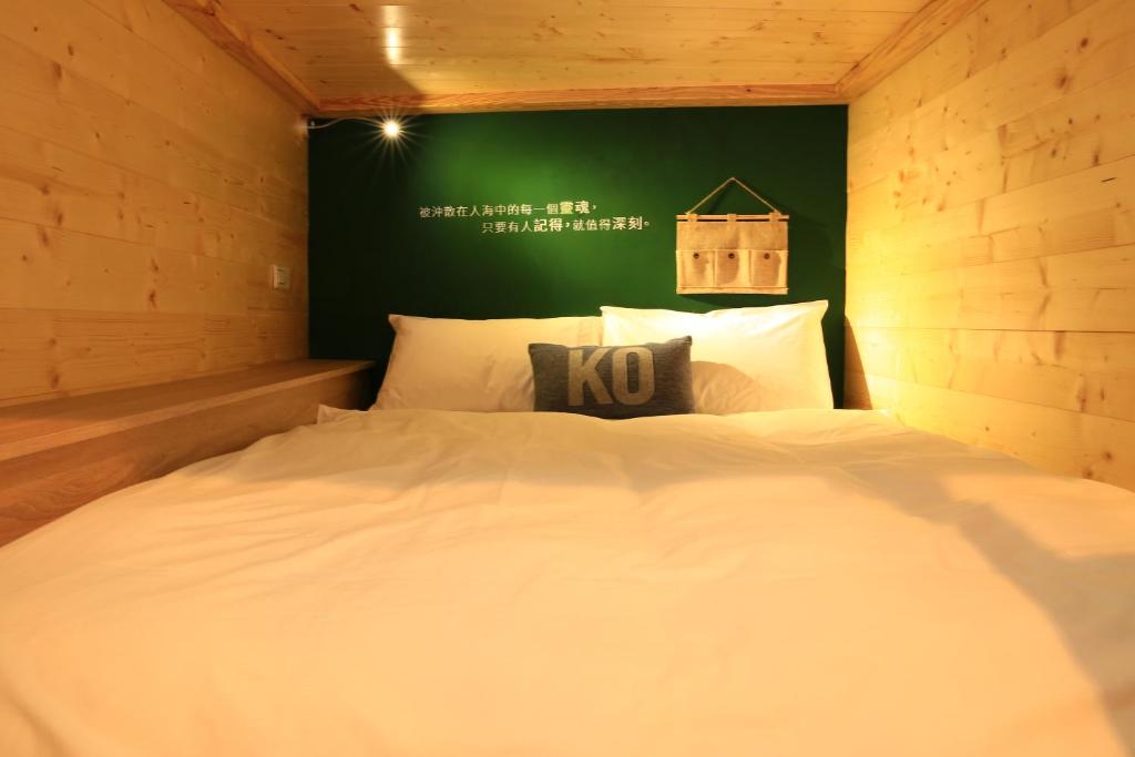 a white bed in a room with a green wall at Kenting Original Hostel in Kenting