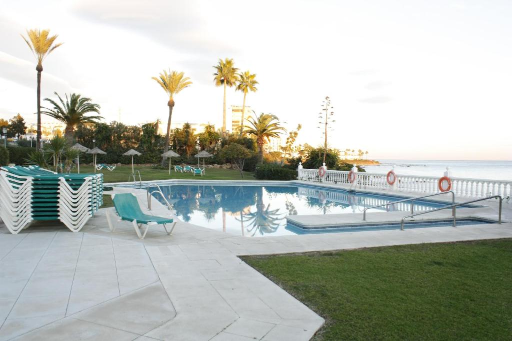 a swimming pool with chairs and the ocean in the background at Luxury in the beach, Lubina Sol in La Cala de Mijas