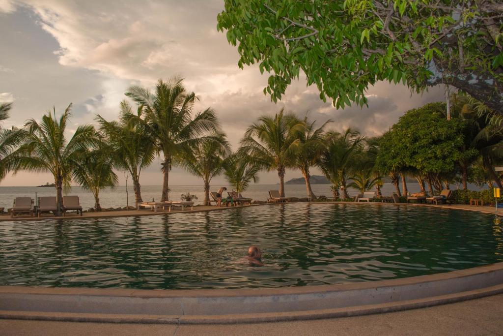 a person swimming in a pool with palm trees at Coral Resort in Ko Chang