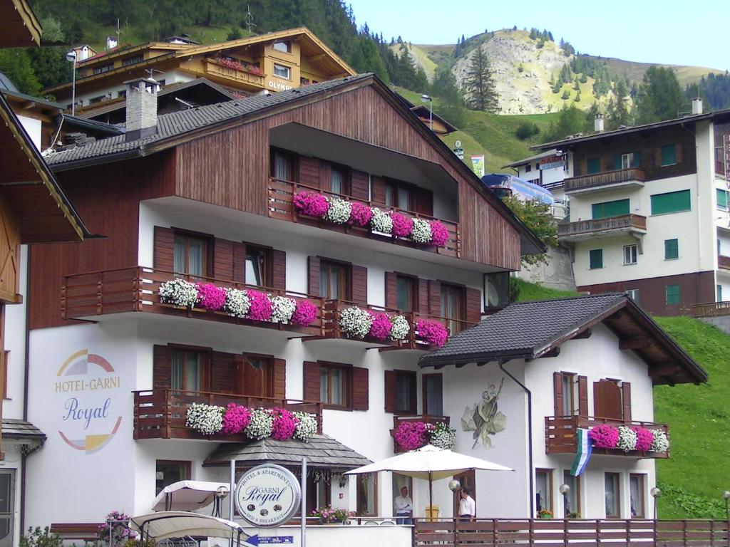 un bâtiment avec des fleurs sur ses balcons dans l'établissement Hotel Garni Royal, à Arabba