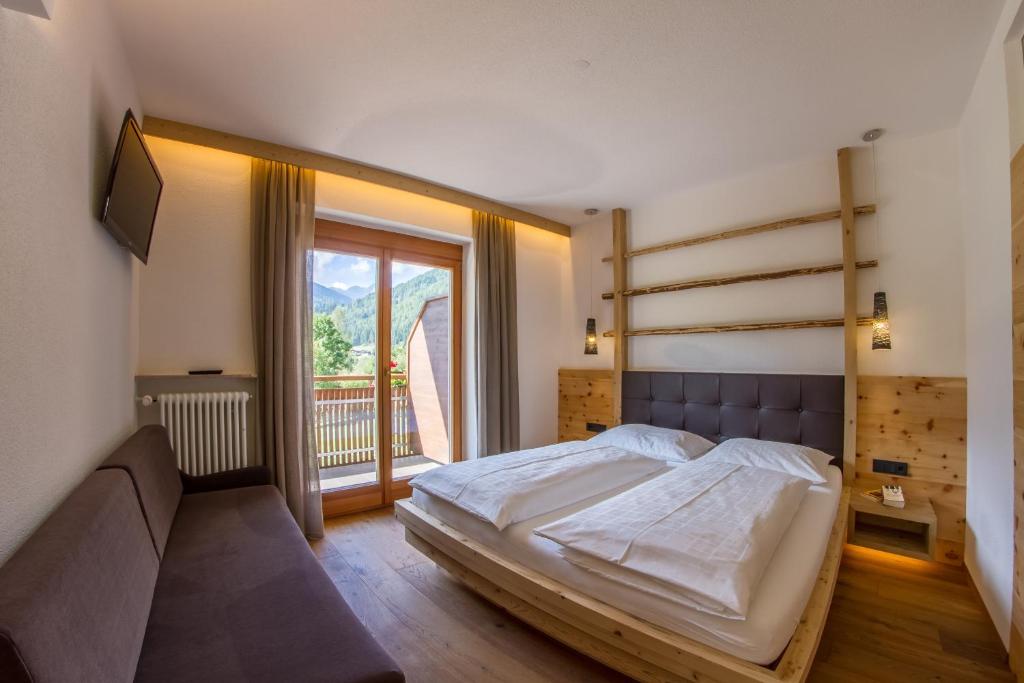 a bedroom with a bed and a large window at Appartement Hotel Erlhof Deluxe in Lutago