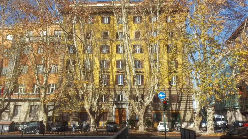ローマにあるVia Veneto Luxury Suitesの目の前の木々が立ち並ぶ黄色い建物