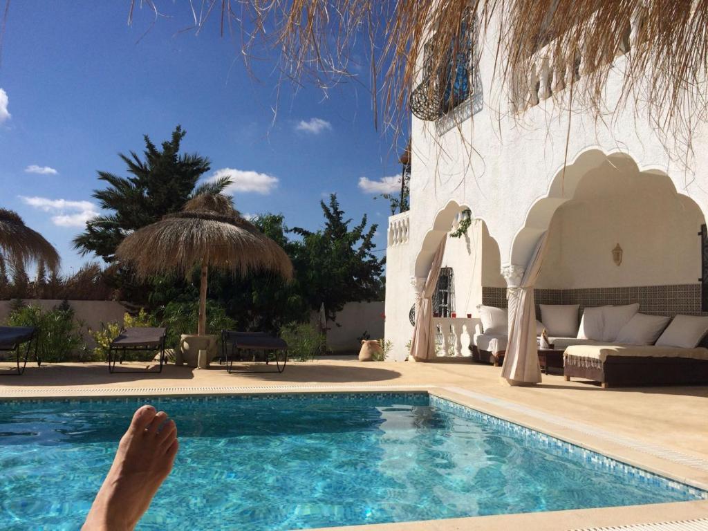 a person laying down next to a swimming pool at Menzel Churasco Djerba in Aghīr