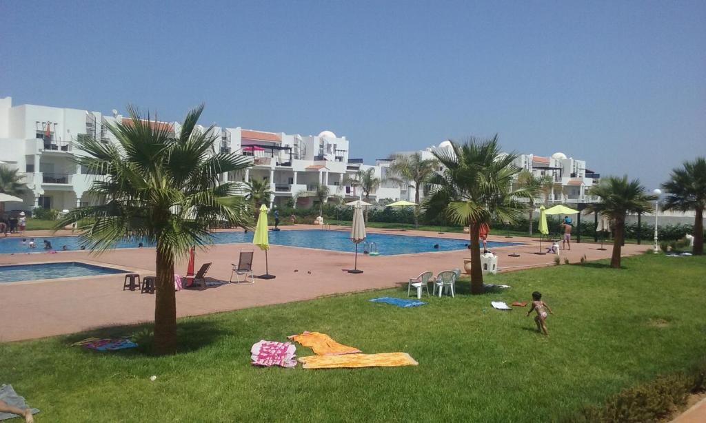 un niño parado en el césped cerca de una piscina en magnifique appartement Saidia, en Saidia 