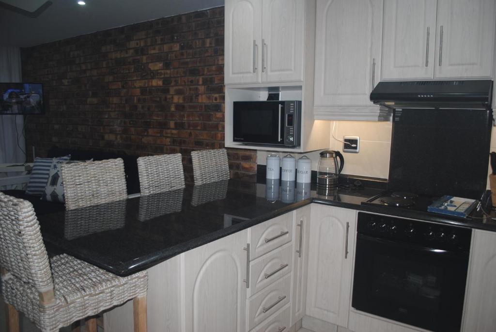 a kitchen with white cabinets and a black counter top at 11 Coral Sands in Scottburgh