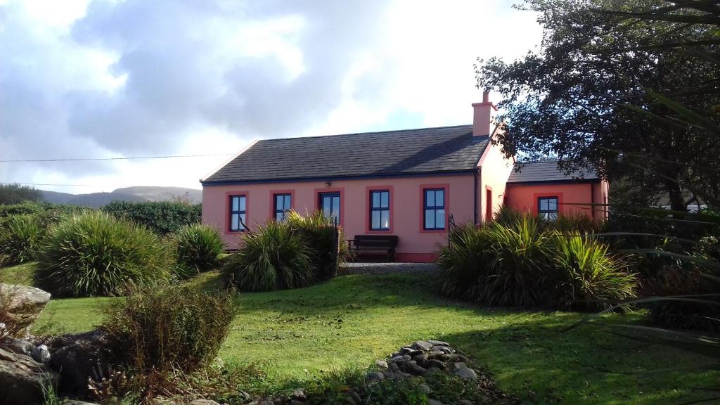 a red house on a grassy yard in front of a house at Manannan Cottage, Beara in Eyeries