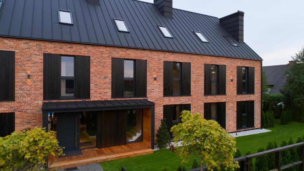 a brick house with a black roof at Klonova in Białogóra