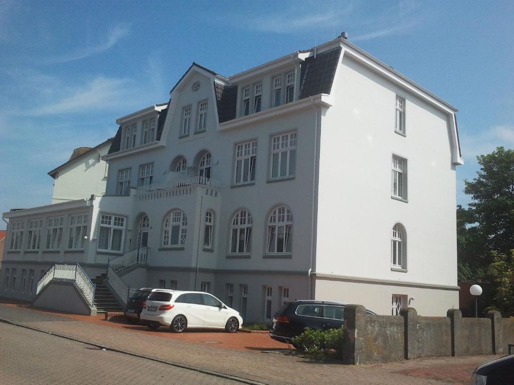 ボルクムにあるStrandvilla zum Erholenの車が目の前に停まった白い建物