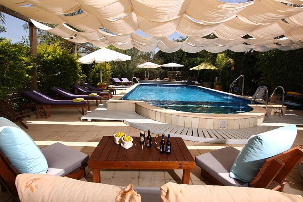 a swimming pool with chairs and a table and a table at Beit Ram Sherf in Moshav Ramot