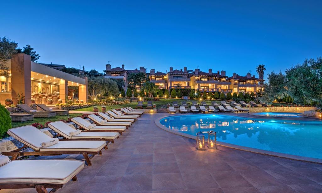 - une piscine avec des chaises longues et un complexe dans l'établissement Kassandra Village Resort, à Pefkohori