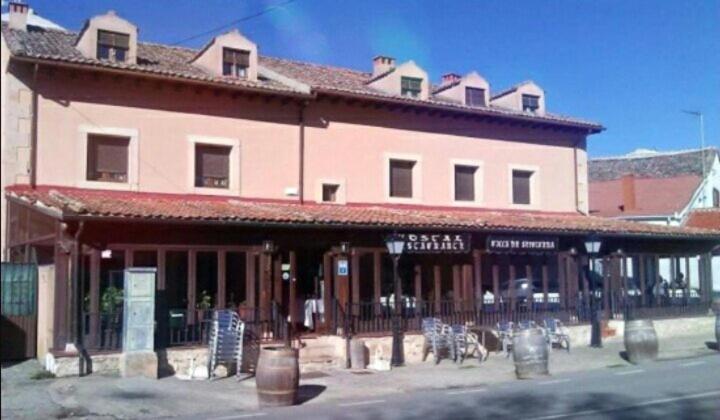 a large building with tables and chairs in front of it at Hostal restaurante Villa de Sepúlveda in Sepúlveda