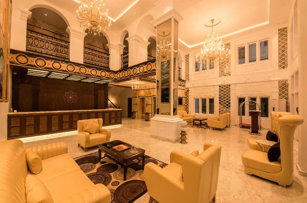 a large lobby with couches and chairs and a stage at White Lotus Hotel in Udupi