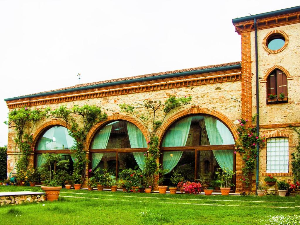 a brick building with green windows and plants at Locanda La Corte Dei Galli in Carre