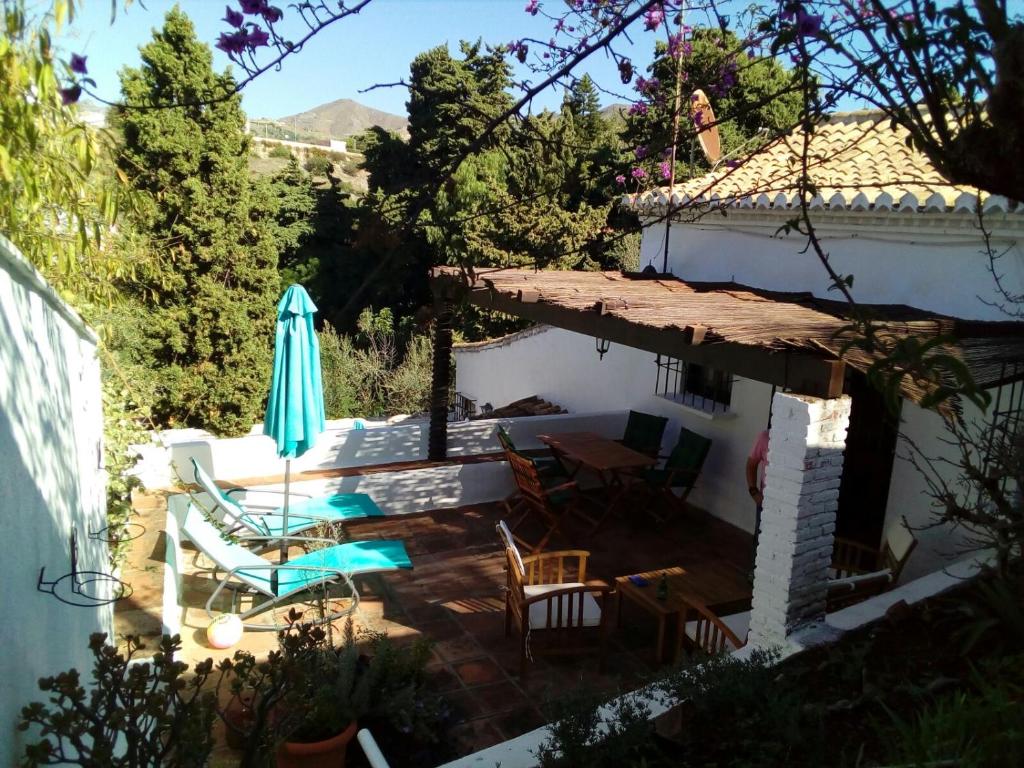 a patio with a table and chairs and an umbrella at Chalecito en la Herradura- Casa Kwetu in La Herradura