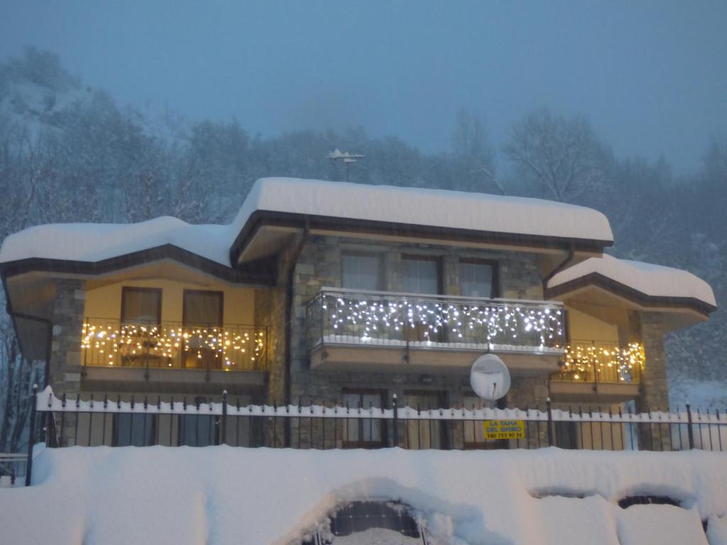 una casa cubierta de luces de Navidad en la nieve en La Tana del Ghiro en Villefranche