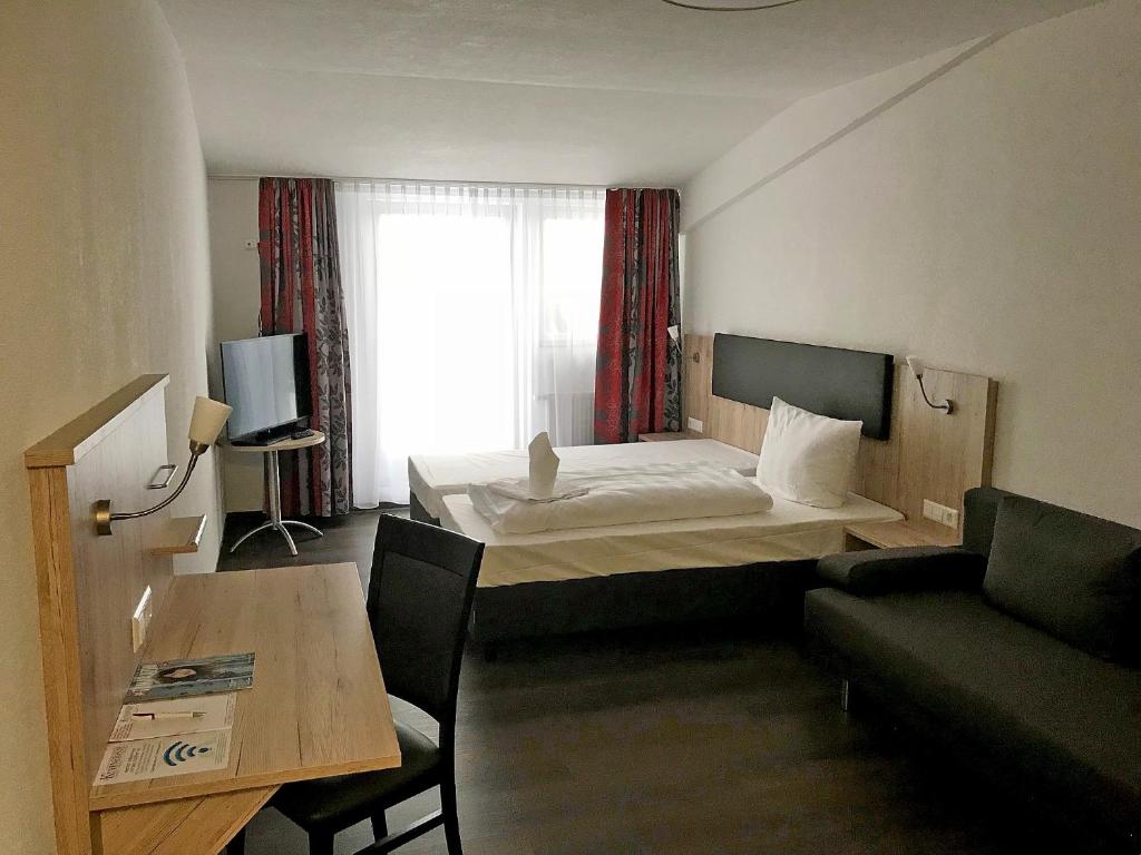 a hotel room with a bed and a couch and a table at Küffner Hof in Langenbeutingen