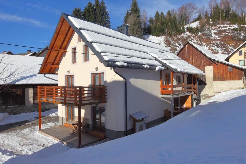 ein Haus mit schneebedecktem Dach im Schnee in der Unterkunft Apartments Planica in Kranjska Gora