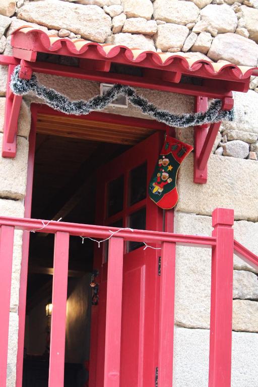 Una puerta roja de un edificio con un cartel. en Casa do Tio João, en Seia