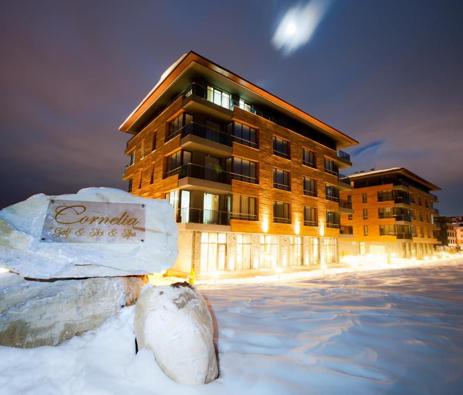 a building in the snow in front of a building at Cornelia Deluxe Residence in Bansko