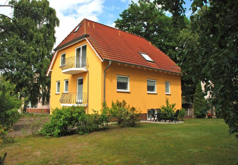 una casa gialla con tetto rosso in un cortile di Ferienapp Dr Beate Gurle Und Dr a Baabe
