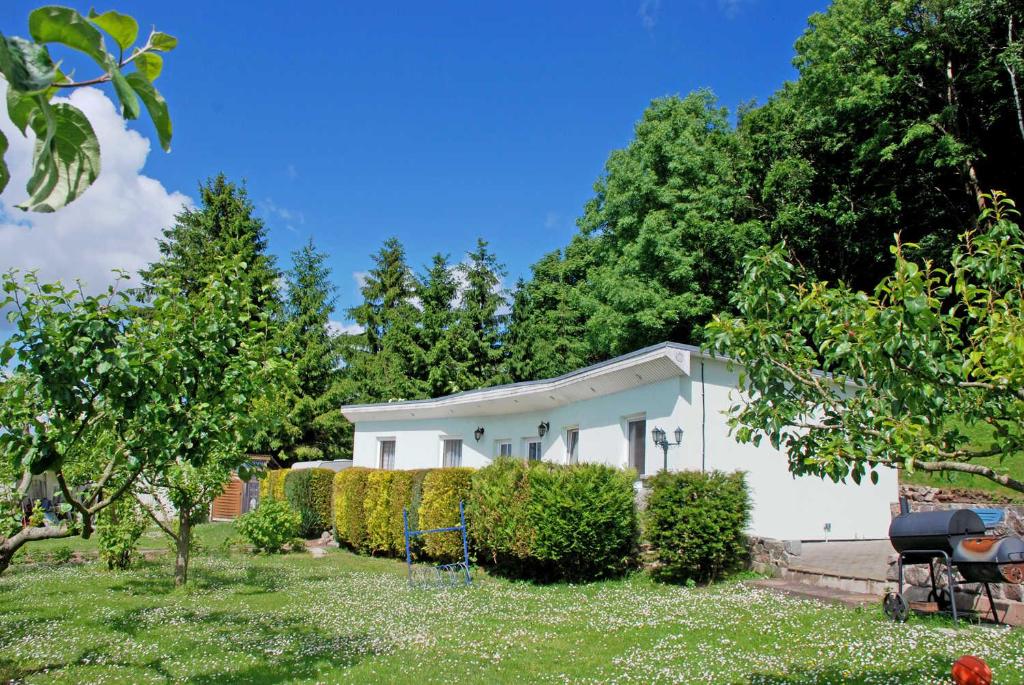 a white house with a hedge in the yard at Ferienwohnung Patzig auf Rügen in Patzig